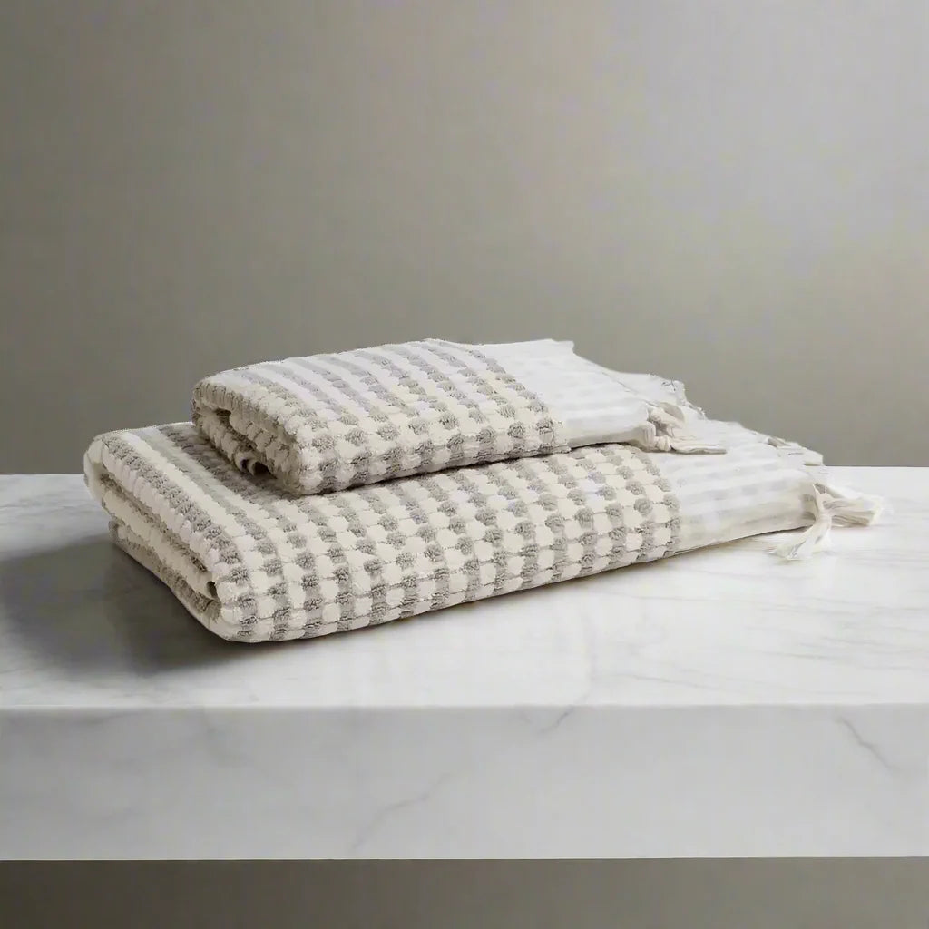 Two folded dotted Turkish terry hand loomed bath towels with striped pattern in taupe