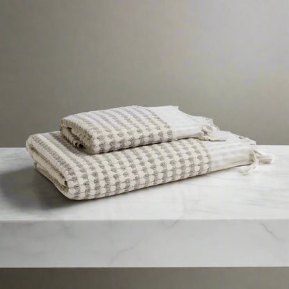Two folded dotted Turkish terry hand loomed bath towels with striped pattern in taupe