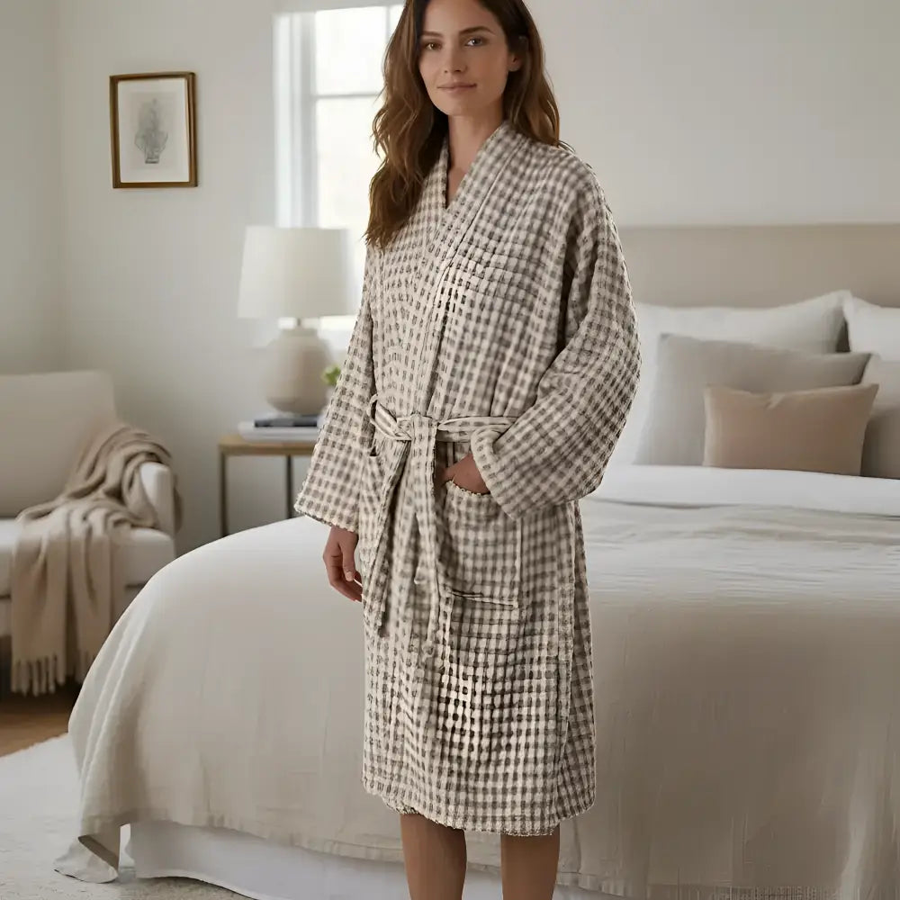 A soft beige and gray checkered bathrobe with cozy knit texture next to a dotted turkish terry hand loomed bath towel taupe