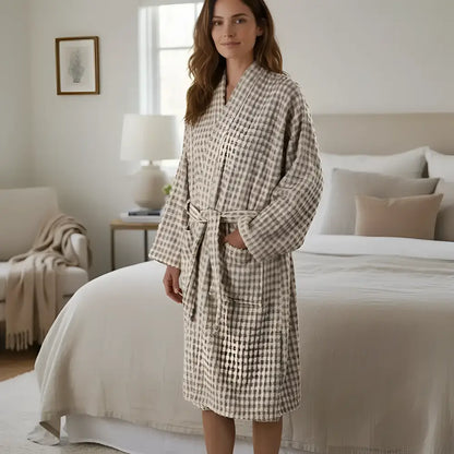 A soft beige and gray checkered bathrobe with cozy knit texture next to a dotted turkish terry hand loomed bath towel taupe
