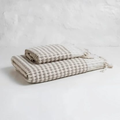 Two folded dotted Turkish terry hand loomed bath towels with striped pattern in taupe