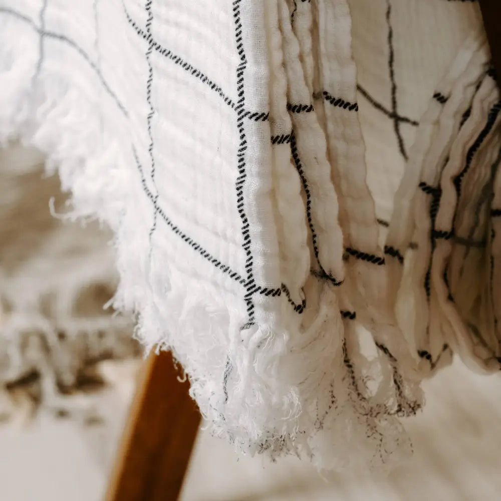 White with charcoal windowpane design 100% cotton muslin oversized throw blanket with fringe.