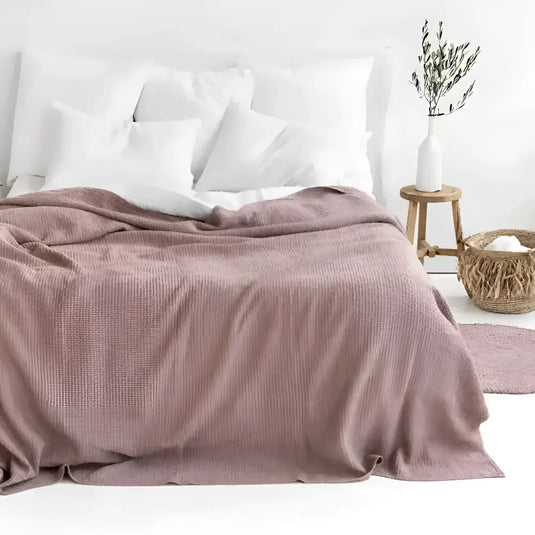 Dusty rose linen-cotton blend waffle blanket with cozy waffle texture on bed