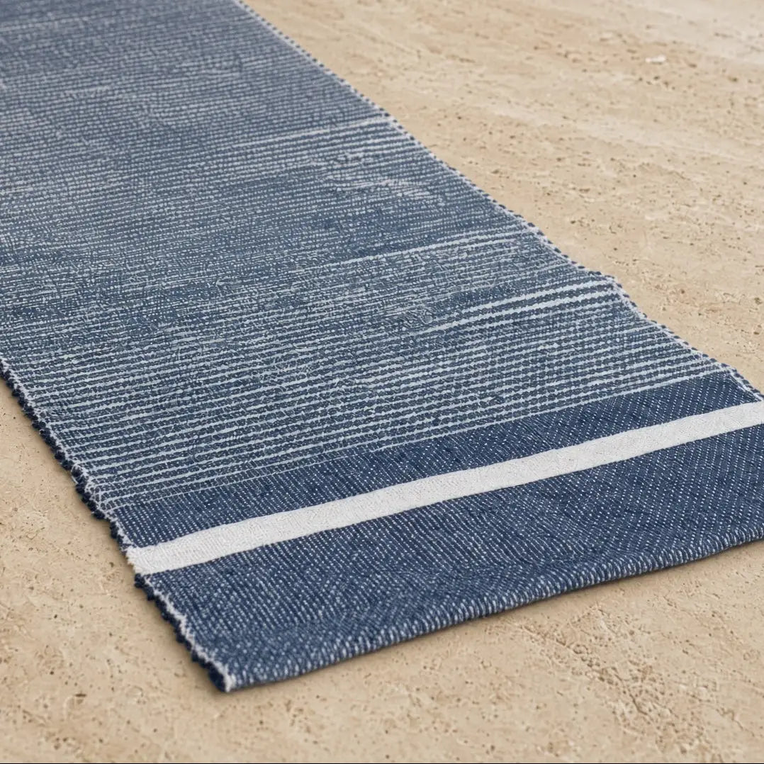 A textured navy blue eco-friendly recycled cotton table runner with a white stripe along one edge