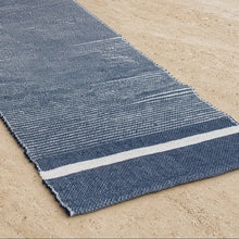 A textured navy blue eco-friendly recycled cotton table runner with a white stripe along one edge
