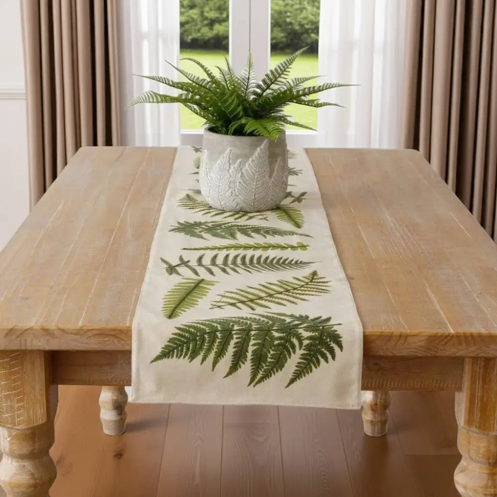 Faux fern plant in textured white pot on embroidered ferns table runner for cozy decor