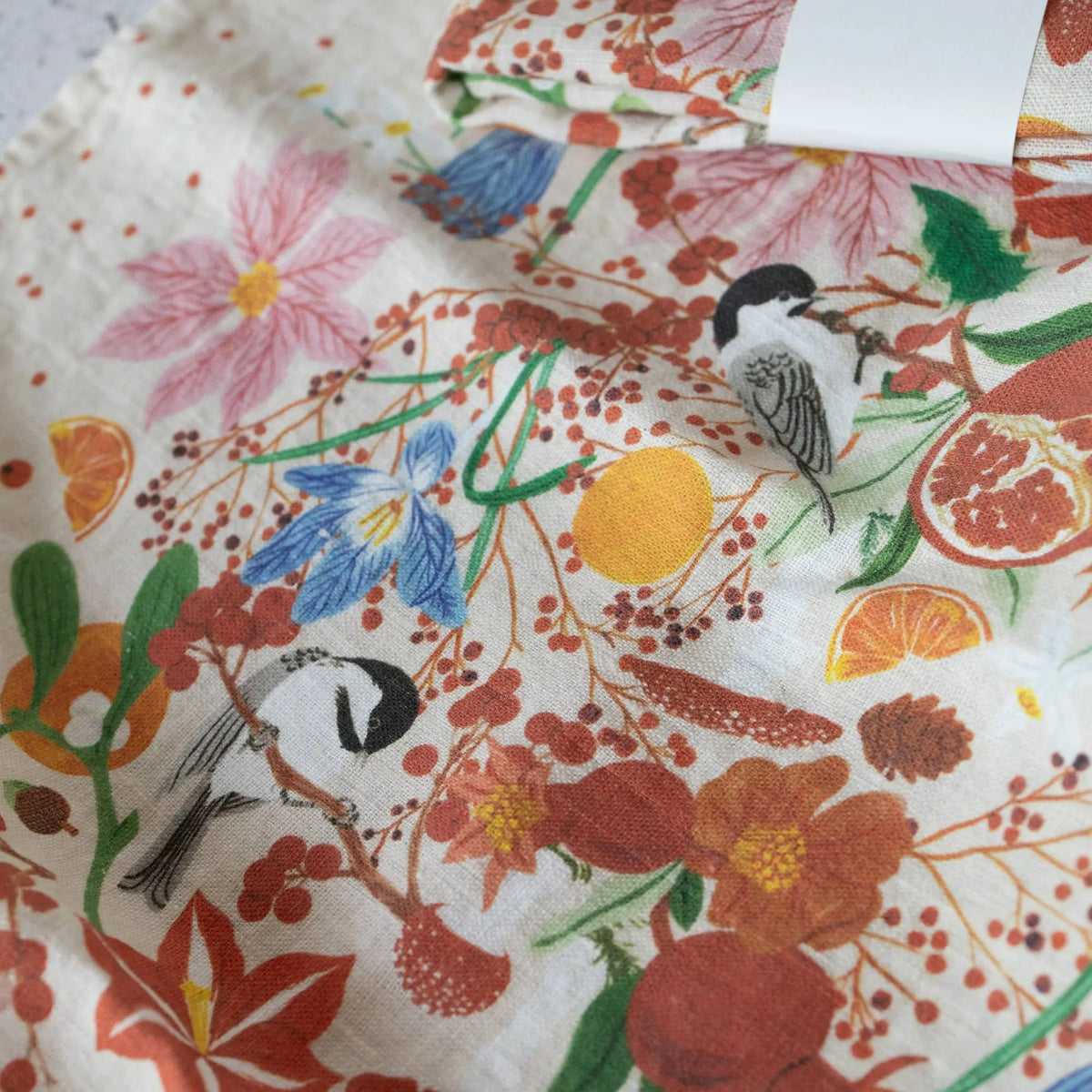 Vibrant floral bird print linen tea towel in oranges, reds, greens on white