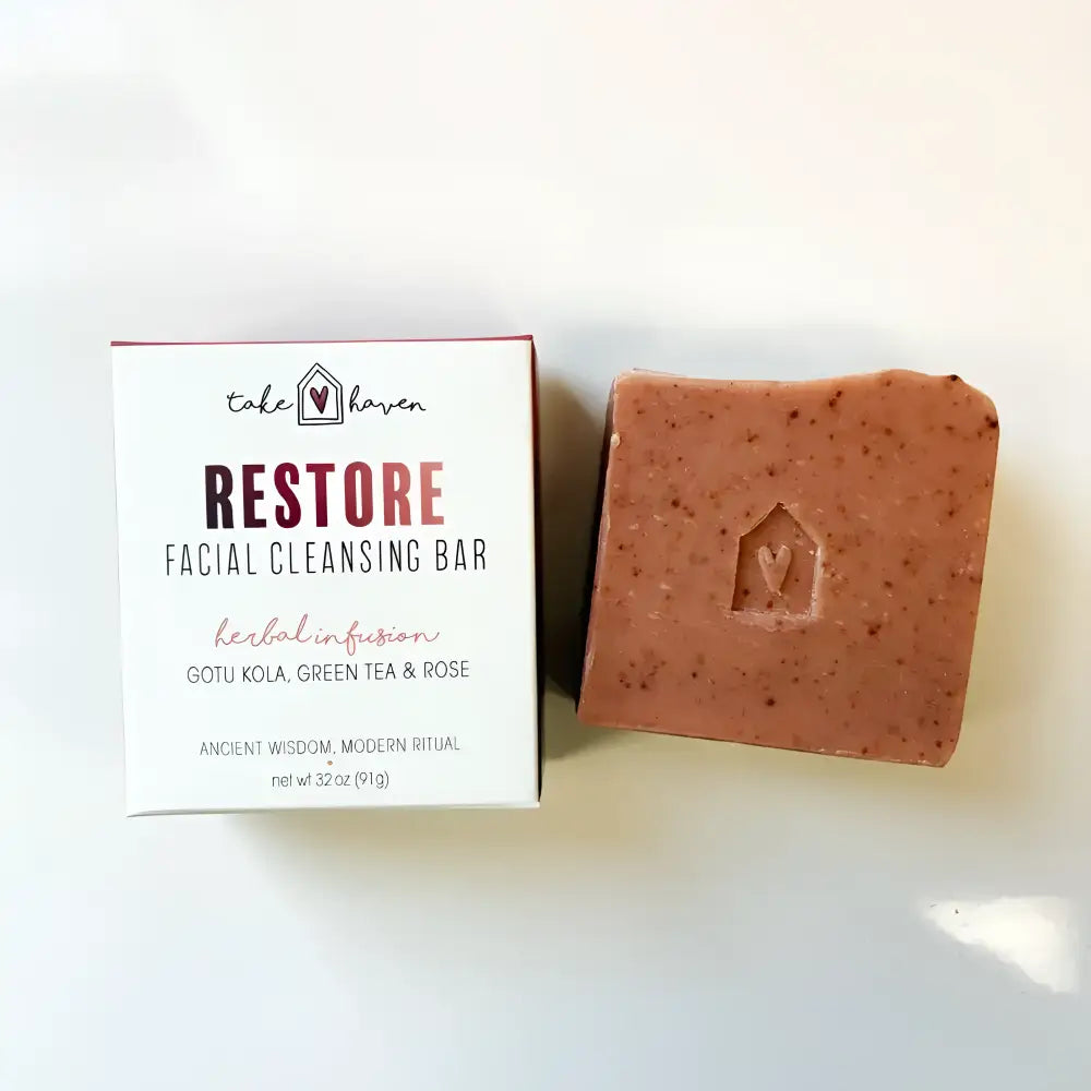 A terracotta speckled facial cleansing bar with rose kaolin clay and western herbalism sits beside its restore packaging