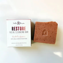 A terracotta speckled facial cleansing bar with rose kaolin clay and western herbalism sits beside its restore packaging