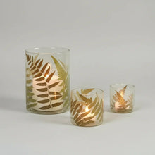 Beautiful fern glass hurricane candle holders with lit candles and golden fern leaf patterns
