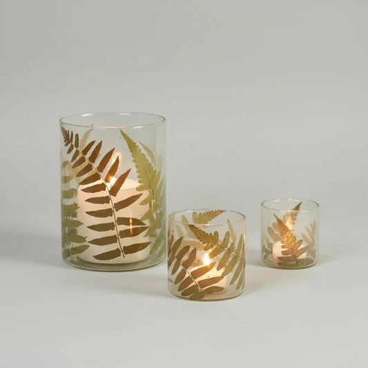 Set of three fern glass hurricane candle holders with golden fern leaf patterns and lit candles