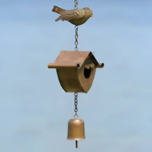 Decorative birdhouse with a bell hanging against a blue sky background