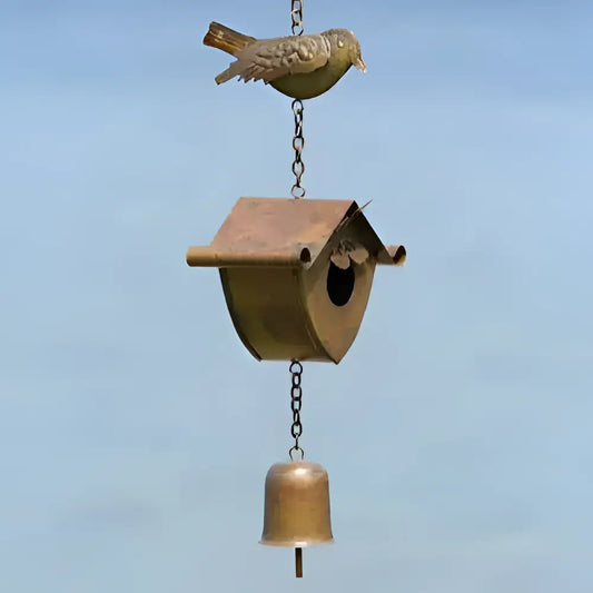 Decorative birdhouse with a bell hanging against a blue sky background
