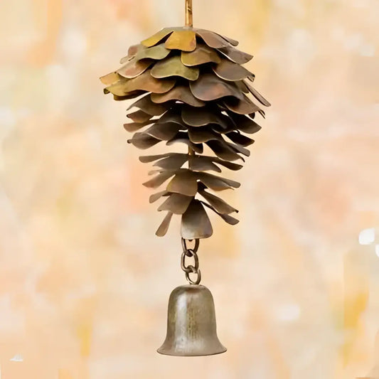 Decorative metal pine cone with a bell on a blurred background