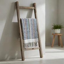 A rustic wooden ladder with a flamingo dotted turkish bath towel featuring multicolored checks and tasseled fringe
