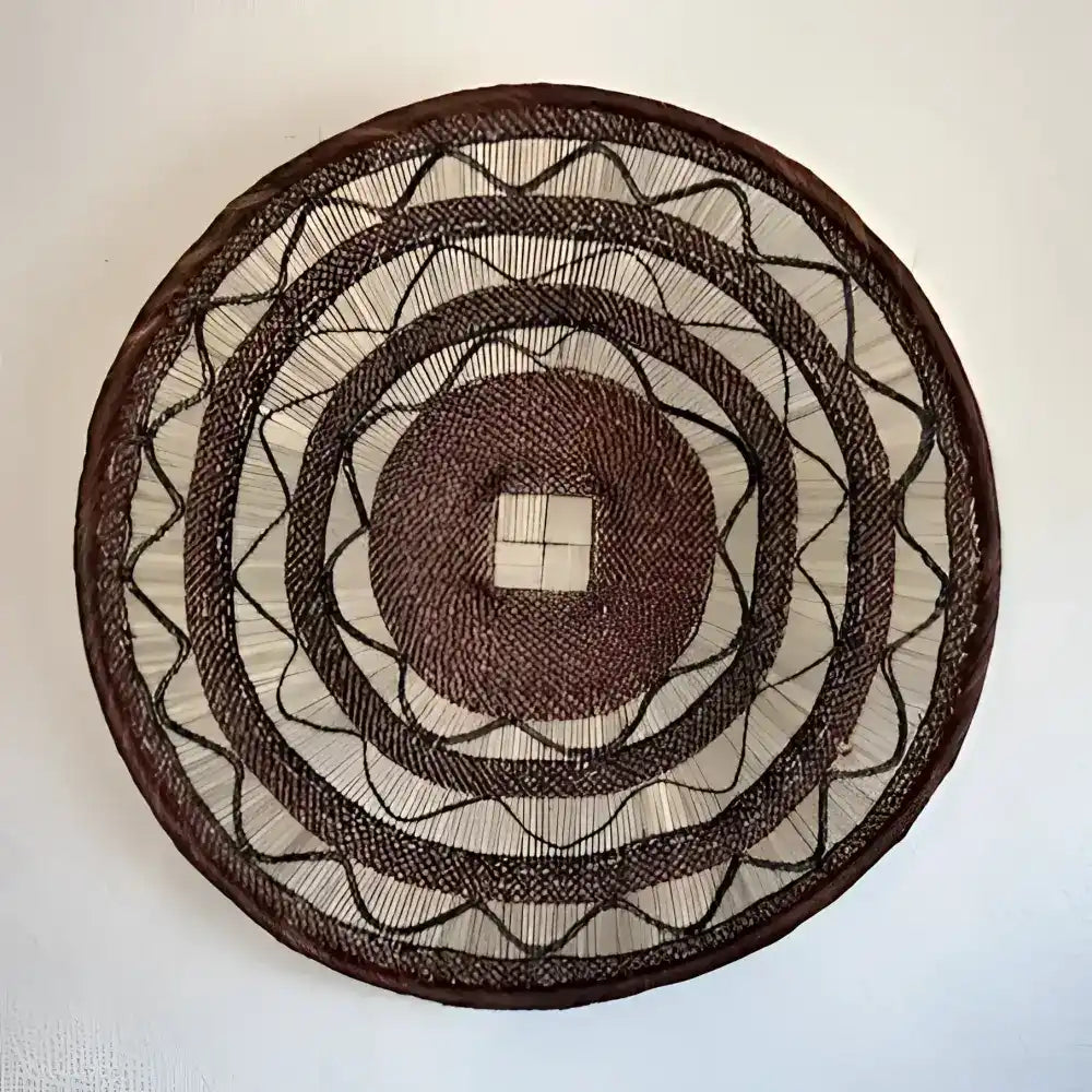 Round woven wall art with concentric circles on a white wall