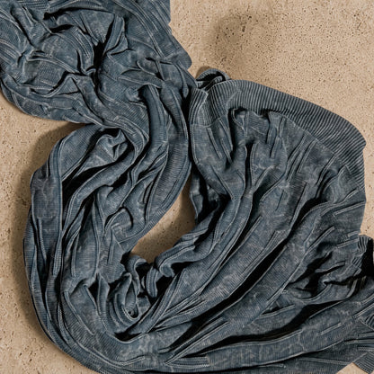 A soft dark gray ribbed knit infinity scarf with textured faded finish paired with flintstone lines washed cotton throw blanket