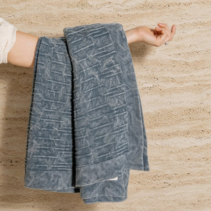 A soft gray flintstone lines throw made of washed cotton with a subtle woven pattern and ribbed edges