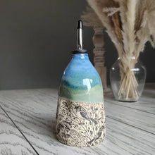 Ceramic oil dispenser with blue green glaze, bird and botanical pattern, metal pour spout