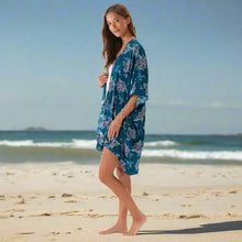 Young woman in teal floral kimono cover up on the beach for a stylish look