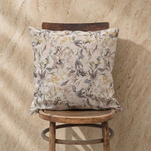 A natural linen pillow with a delicate watercolor botanical print in muted greens on light beige linen fabric ideal for low heat care