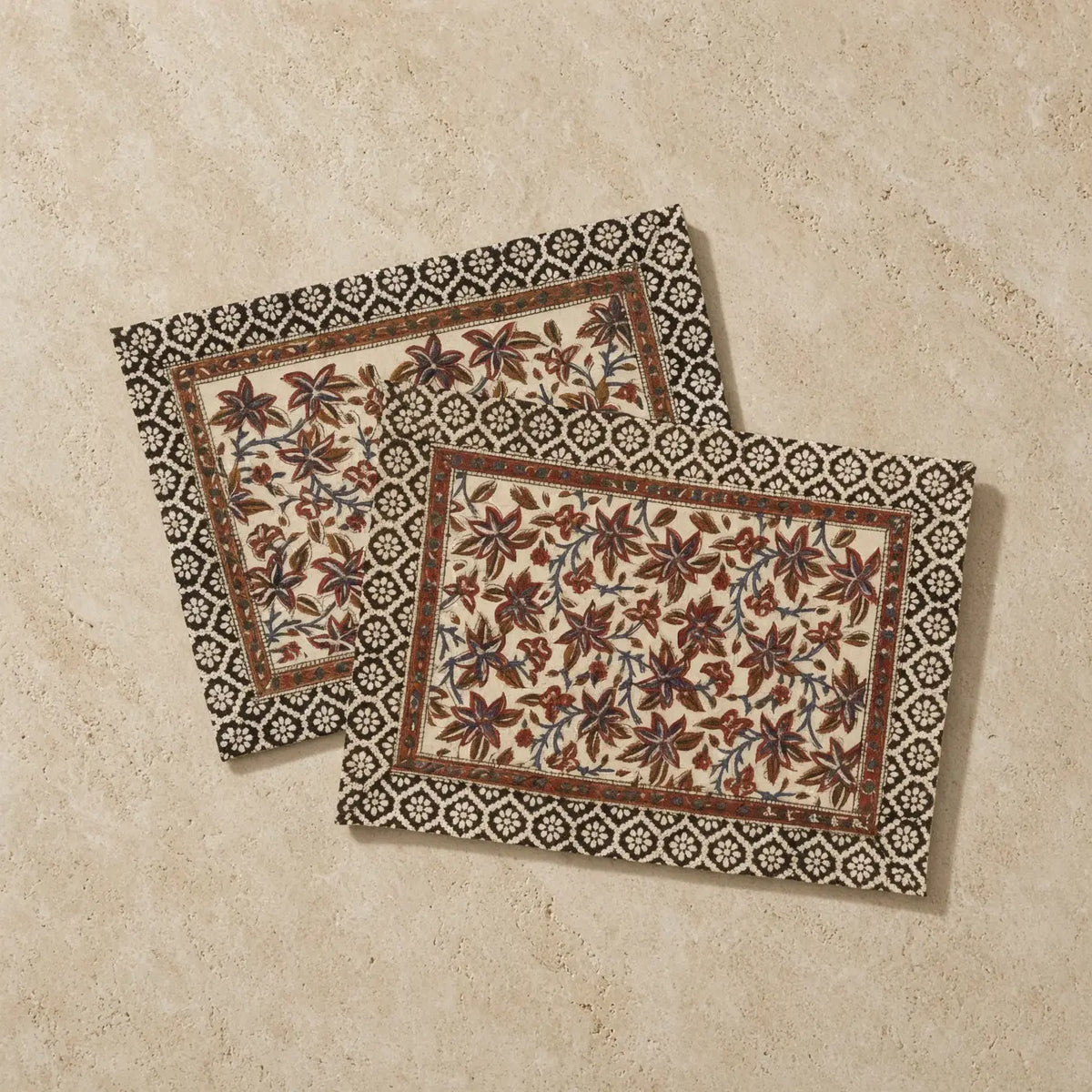 Beige cotton vines placemats set with intricate brown and black floral embroidery and decorative geometric border