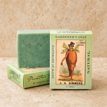 A mint-green speckled handmade soap bar in an eco-friendly light green box with a carrot man illustration