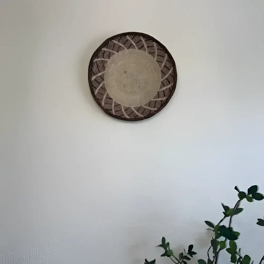 Decorative woven basket on a white wall with a plant in the corner
