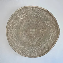 Woven basket with geometric pattern on a light gray background