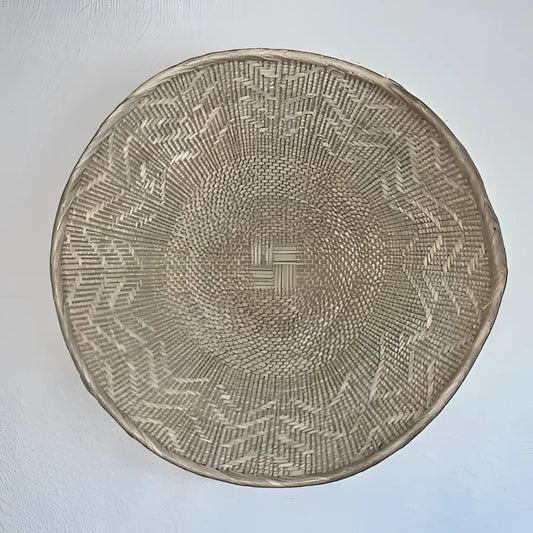 Woven basket with geometric pattern on a light gray background