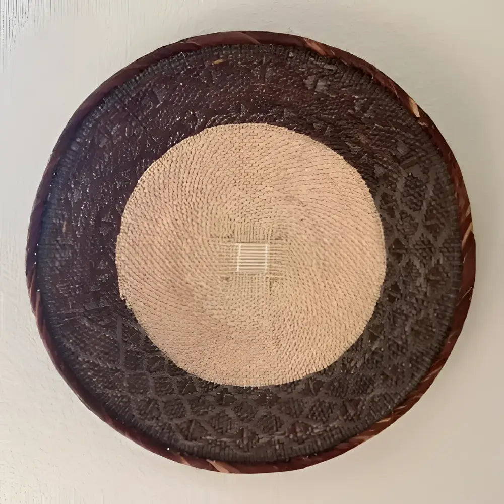 Round woven basket with a beige center and dark brown border on a light background