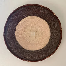 Round woven basket with a beige center and dark brown border on a light background