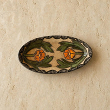 An oval handcrafted ceramic trinket dish with globe mallow sgraffito featuring orange poppies and a dark brown scalloped border