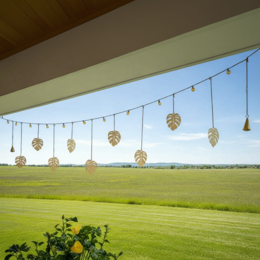 Handmade golden monstera garland with eco-friendly clear coat, hanging from lights outdoors