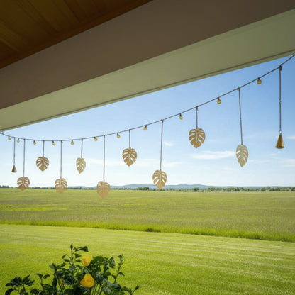 Handmade golden monstera garland with eco-friendly clear coat, hanging from lights outdoors