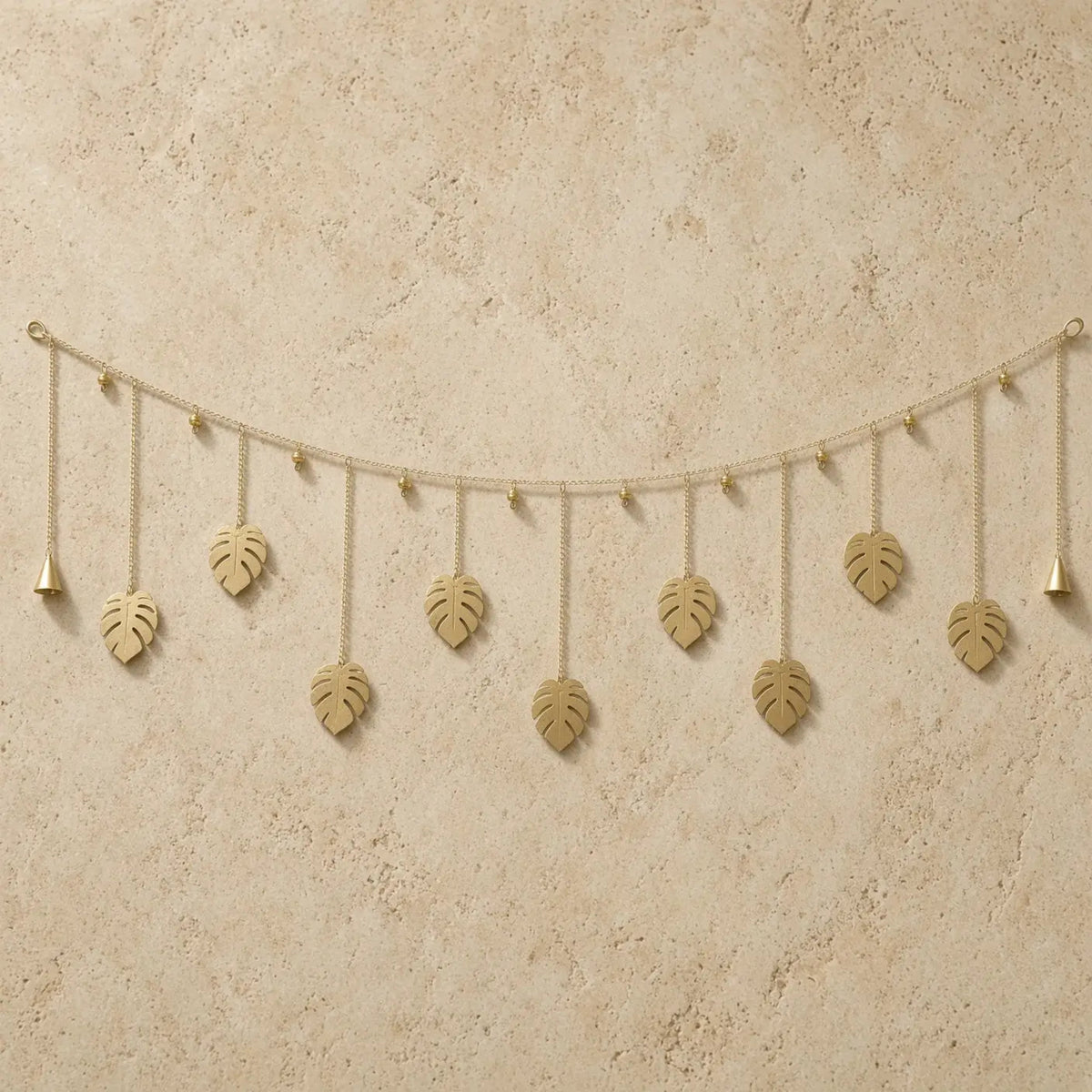 Golden monstera leaf whimsical garland made of reused metal with dangling bells for wall decor