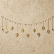 Golden monstera leaf whimsical garland made of reused metal with dangling bells for wall decor