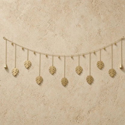 Golden monstera leaf whimsical garland made of reused metal with dangling bells for wall decor