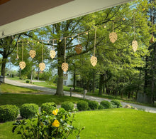 Handmade golden monstera garland with eco-friendly clear coat, hanging from lights outdoors