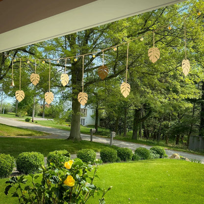 Handmade golden monstera garland with eco-friendly clear coat, hanging from lights outdoors