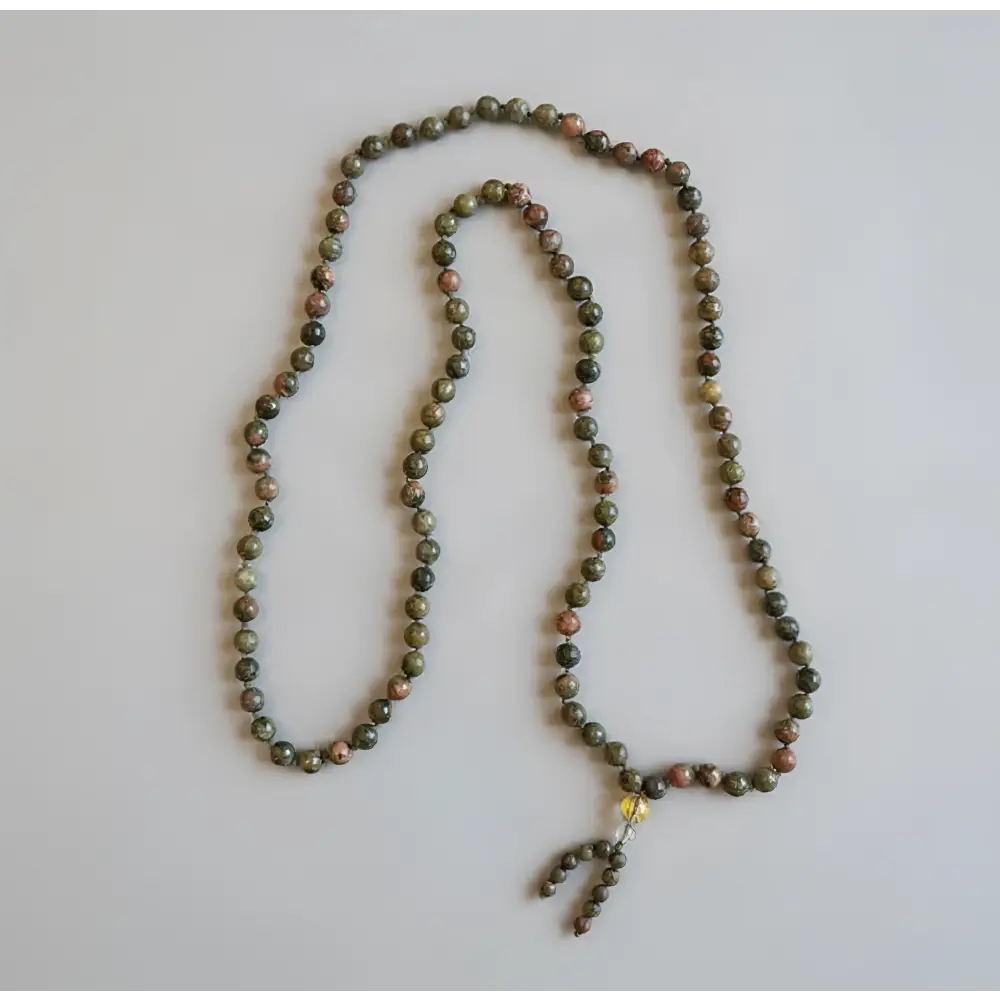 A green unakite mala necklace with 8 mm smooth stones and a beaded tassel designed to support emotional healing