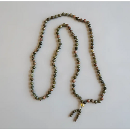A green unakite mala necklace with 8 mm smooth stones and a beaded tassel designed to support emotional healing