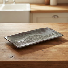 Decorative rectangular plate with a textured design on a white surface.