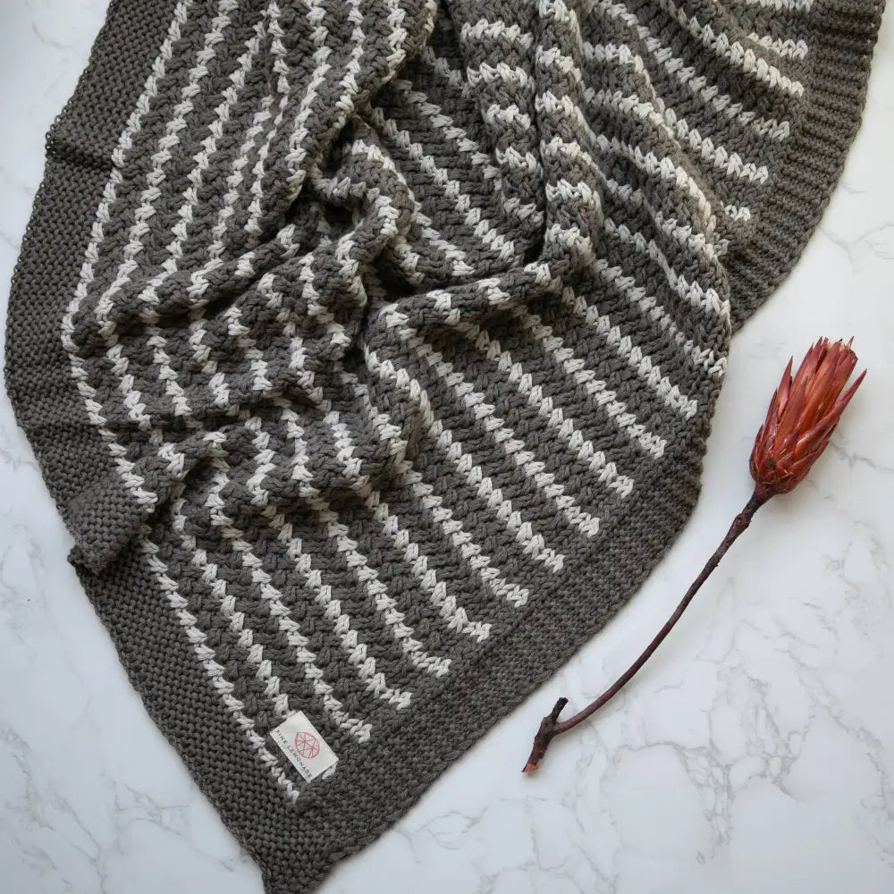 Grey and white zigzag knit cotton throw blanket with floral tag