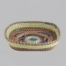 Intricately woven basket of native wild grass, and pine needles with colorful raffia accents.
