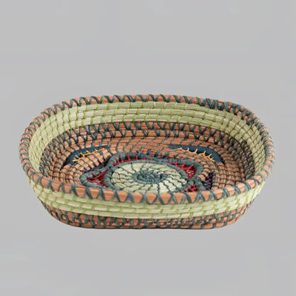Intricately woven basket of native wild grass, and pine needles with colorful raffia accents.