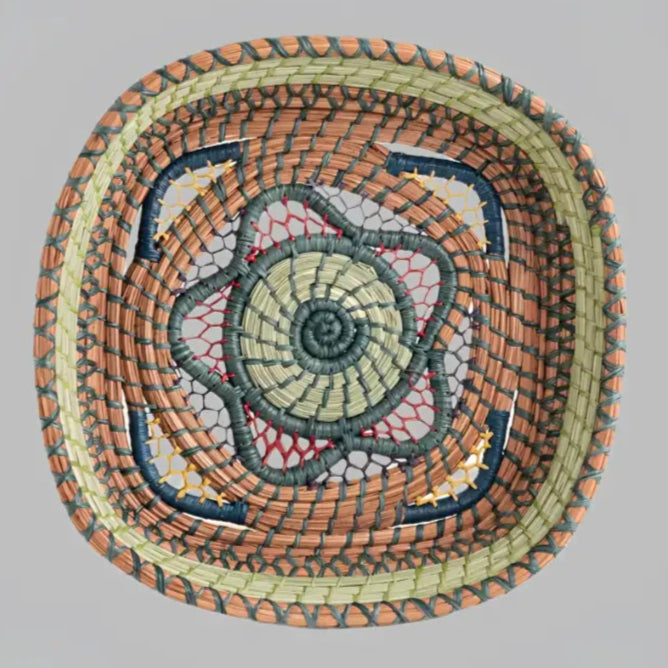 Intricately woven basket of native wild grass, and pine needles with colorful raffia accents.
