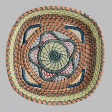 Intricately woven basket of native wild grass, and pine needles with colorful raffia accents.