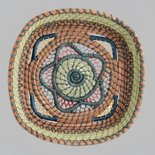 Intricately woven basket of native wild grass, and pine needles with colorful raffia accents.