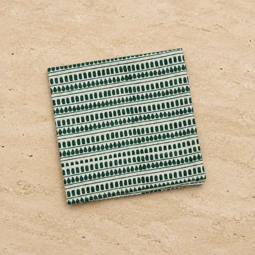 A folded hand block printed organic cotton napkin shines with teal dotted striped pattern and azo-free pigments cream dots
